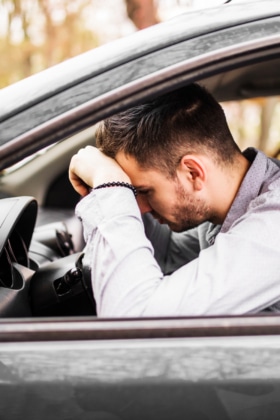 Young man sitting in car very upset and stressed after hard fail